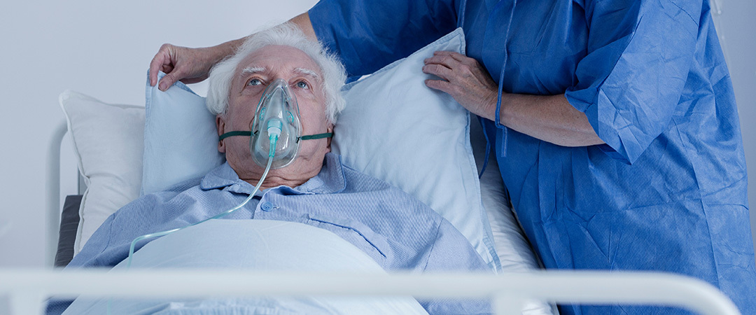 Man lying in a hospital bed with a ventilator on